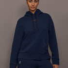 Model is wearing On Focus Tech Hoodie for women in navy with drawstring hood, kangaroo pocket, and relaxed fit, front view.