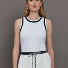 Model wears a white tank top with green trim, perfect for tennis.