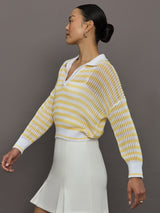 Model wears a lightweight collared open knit yellow and white striped sweater. 