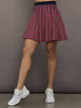 Model wears a red and blue patterned pleated high waisted tennis skirt. 