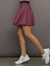 Model wears a red and blue patterned pleated high waisted tennis skirt. 