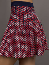 Model wears a red and blue patterned pleated high waisted tennis skirt. 