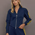 Model is wearing the Miaou tracktop in collegiate navy with a cropped silhouette a full zip front and contrast yellow stripe detailing.