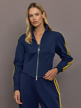 Model is wearing the Miaou tracktop in collegiate navy with a cropped silhouette a full zip front and contrast yellow stripe detailing.