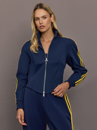 Model is wearing the Miaou tracktop in collegiate navy with a cropped silhouette a full zip front and contrast yellow stripe detailing.