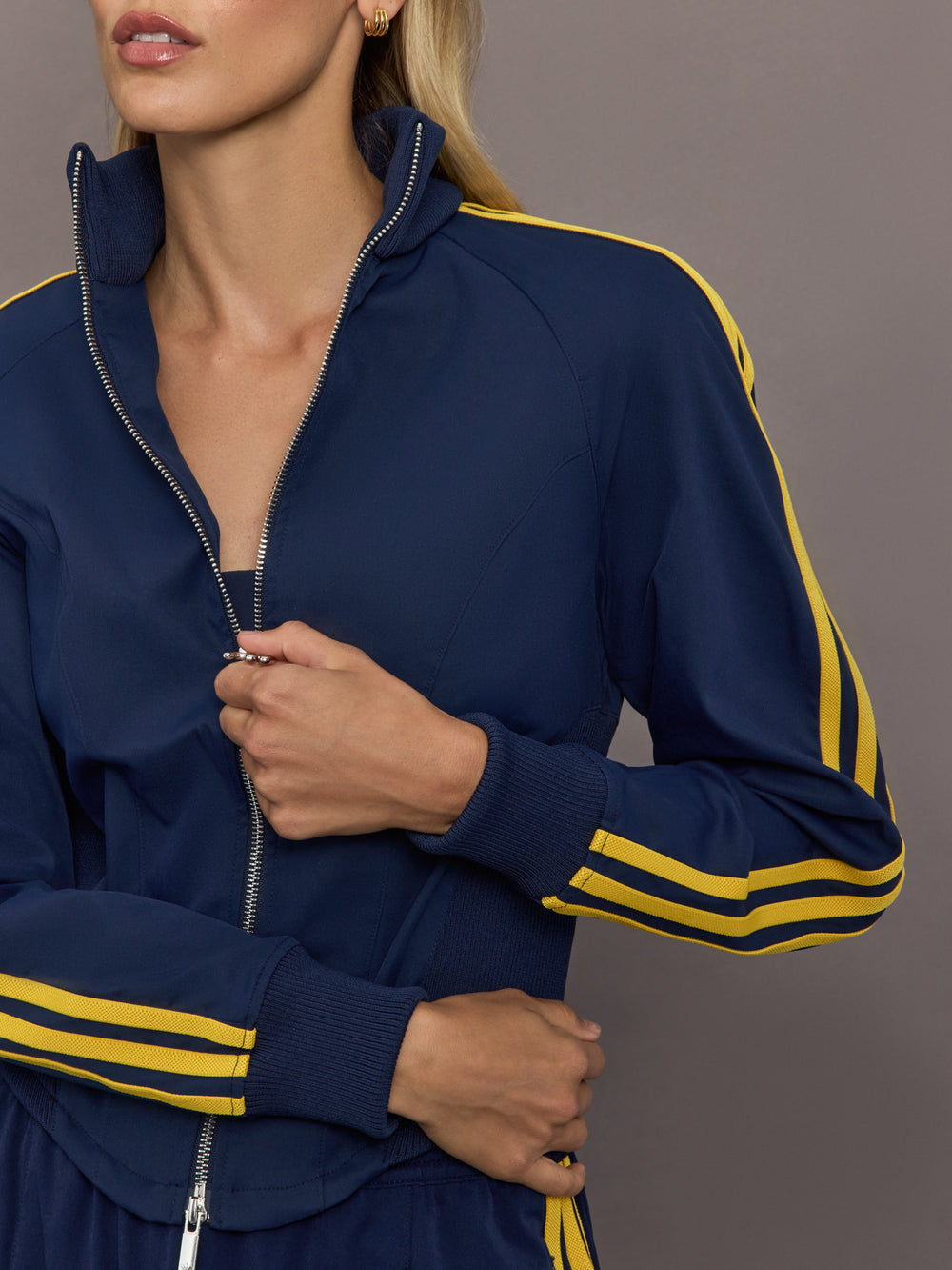 Close up of the Miaou tracktop in collegiate navy featuring the zip front high collar and contrast stripe sleeves.