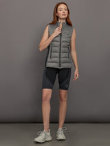 Model wears sleeveless grey golf vest with a high collar, front zipper, and side zip pockets.
