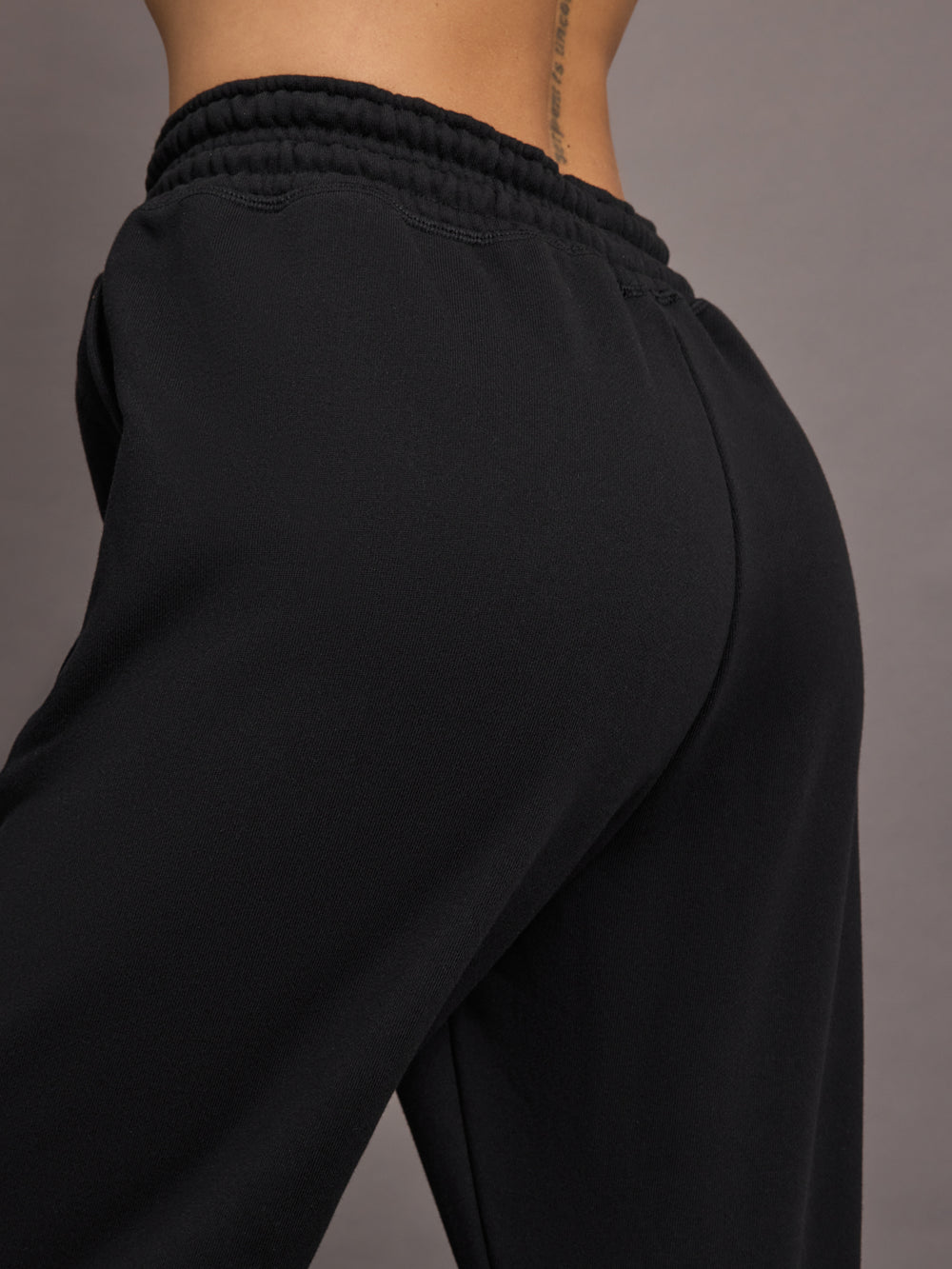 Model is wearing black jogger sweatpants with drawstring and pockets