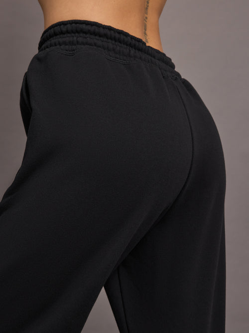 Model is wearing black jogger sweatpants with drawstring and pockets