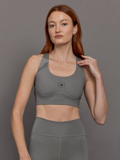 Model wears grey sports bra with a racerback design, mesh panels, and small laser-cut holes.




