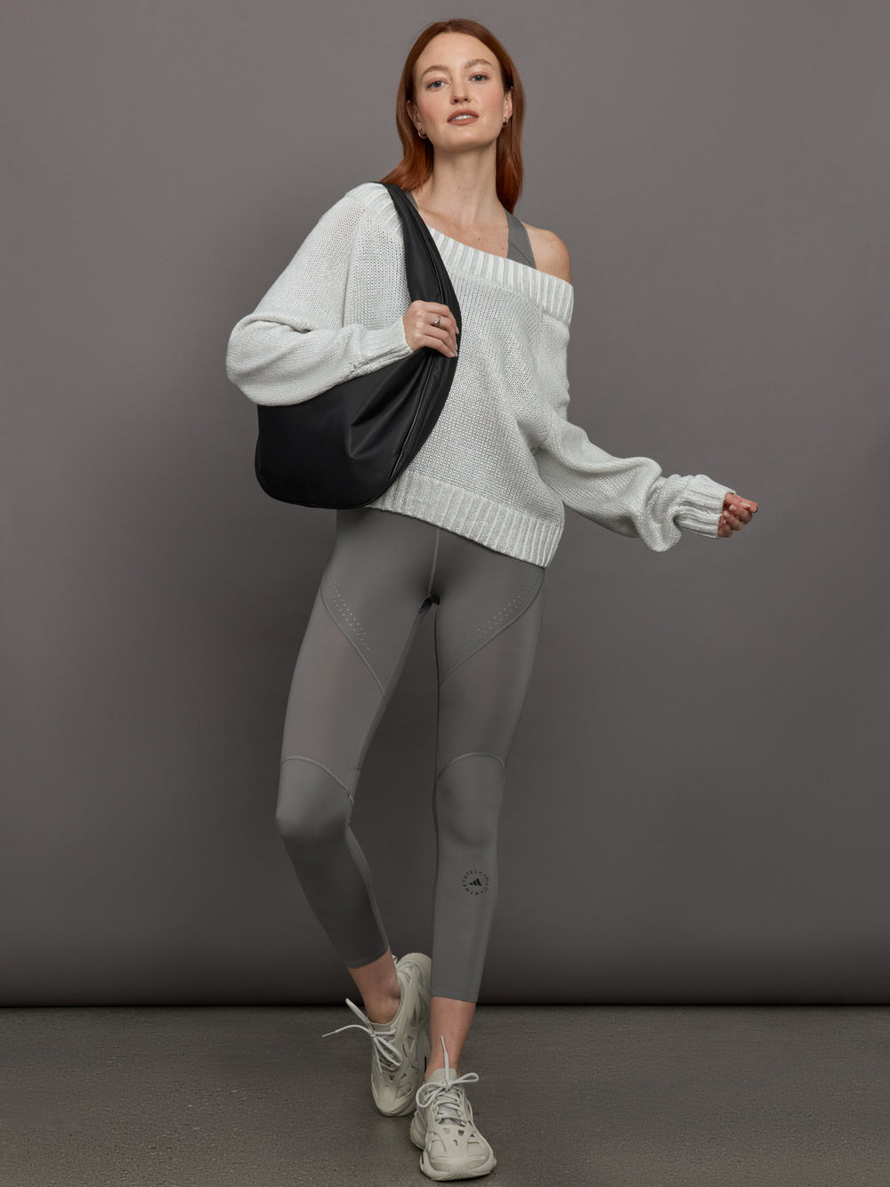 Model wears high-rise grey leggings with a wide elastic waistband, laser-cut perforations, and a small back pocket.
