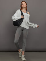 Model wears high-rise grey leggings with a wide elastic waistband, laser-cut perforations, and a small back pocket.
