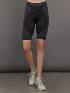 Model wears black and dark grey two-tone biker shorts with a high-rise waistband and an open side pocket.




