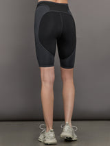 Model wears black and dark grey two-tone biker shorts with a high-rise waistband and an open side pocket.
