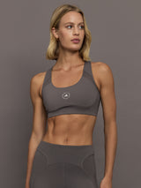 Woman wearing a gray sports bra with white a brand logo.
