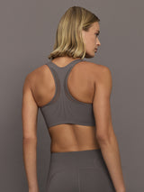 Woman wearing a gray sports bra with white a brand logo.