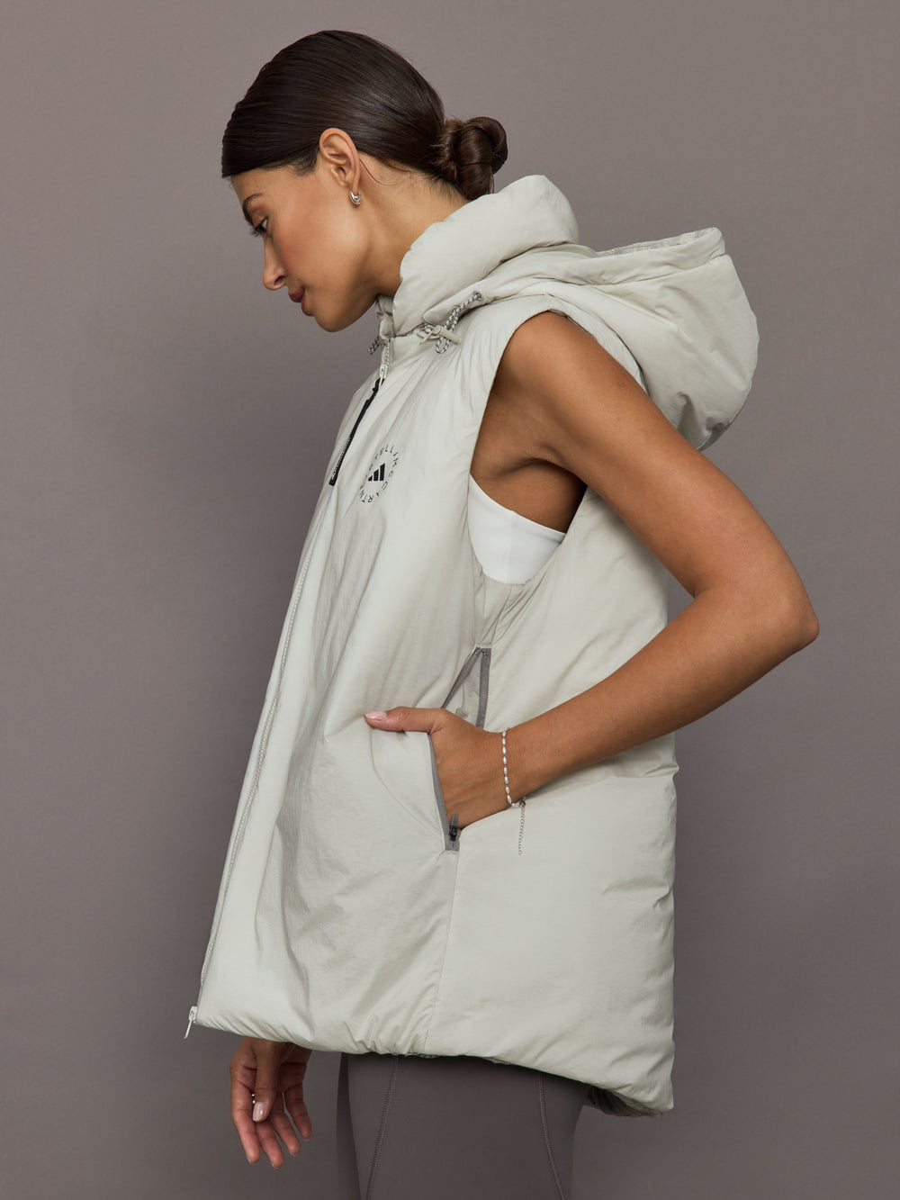 Woman wearing a light gray puffer vest against a plain background