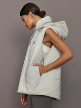 Woman wearing a light gray puffer vest against a plain background