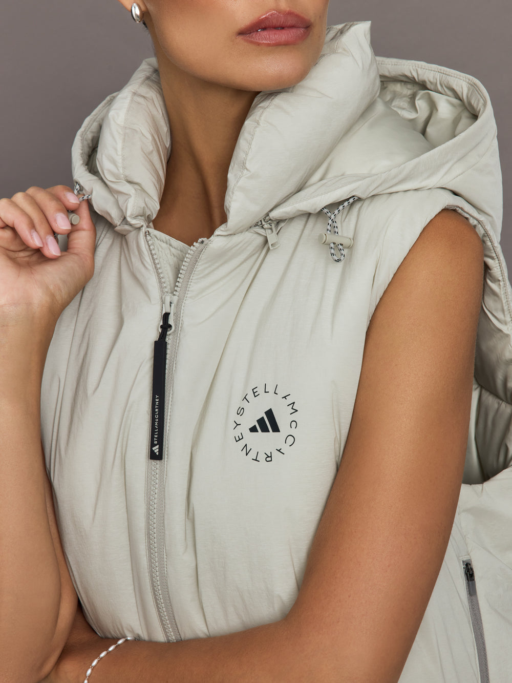 Light gray sleeveless puffer vest with Adidas logo on a neutral background