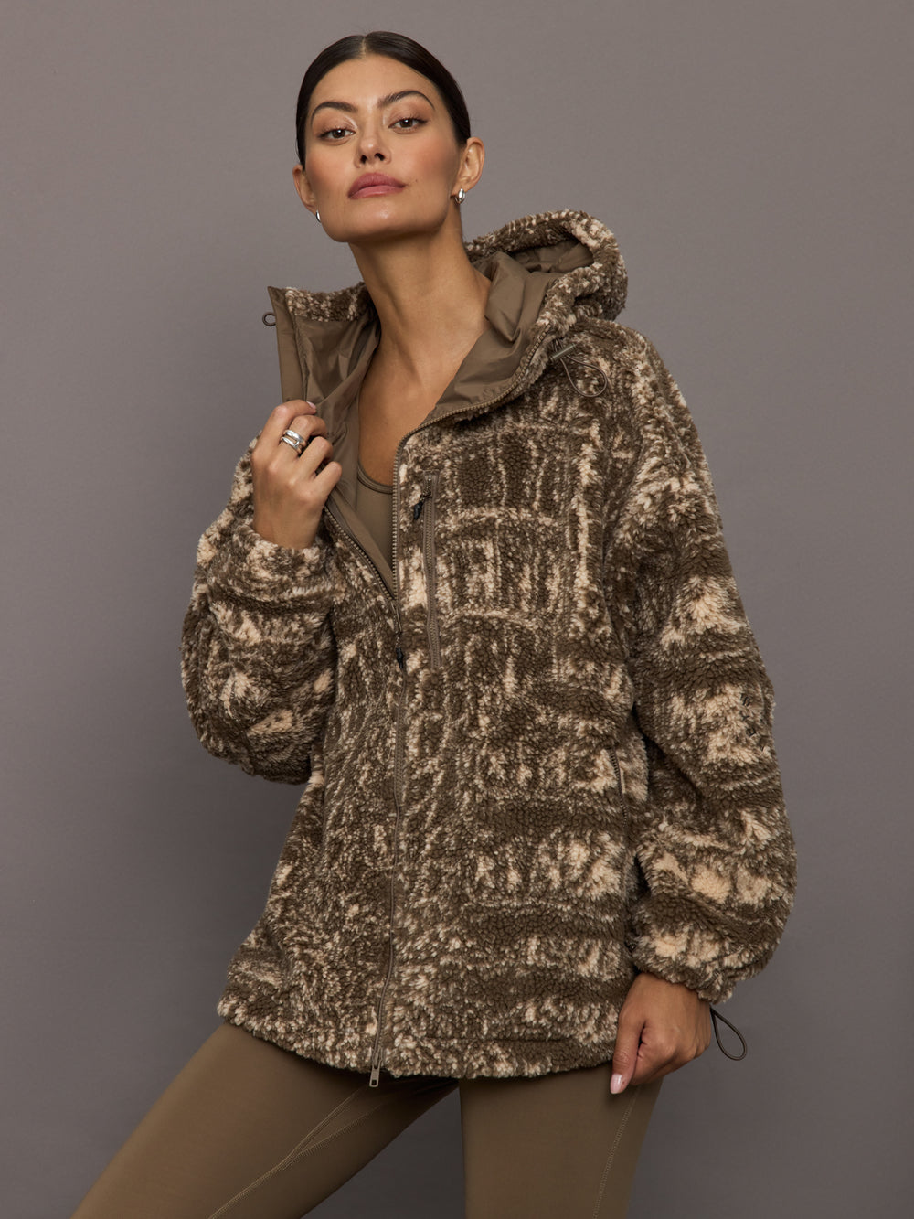 Woman wearing a patterned jacket against a gray background