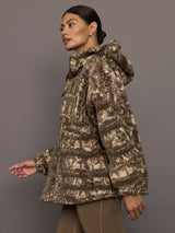 Woman wearing a patterned jacket against a gray background