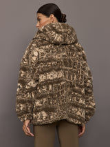 Person wearing a patterned coat against a gray background