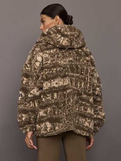 Person wearing a patterned coat against a gray background