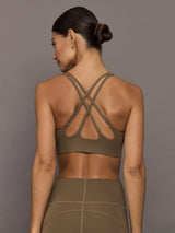 Woman wearing a brown sports bra and leggings against a gray background