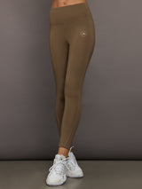 Person wearing brown leggings with a logo on a gray background