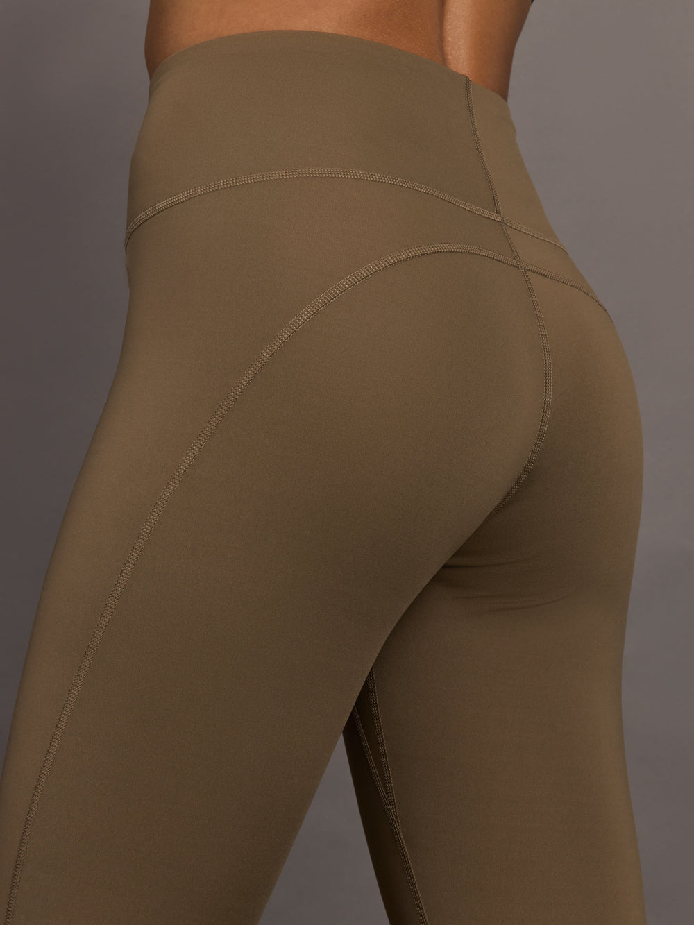 Brown leggings worn by a person on a gray background