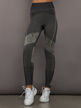 Person wearing black and gray leggings with a patterned snakeskin design on a gray background