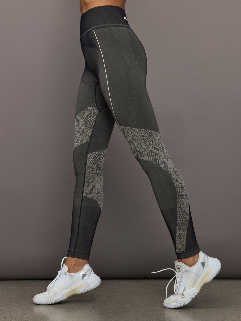 Dark gray leggings with patterned design worn by a person on a plain background