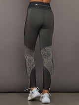 Person wearing dark gray leggings with snake print pattern on a gray background