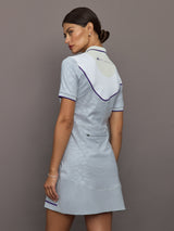 Woman wearing a light gray dress with a collar against a plain background
