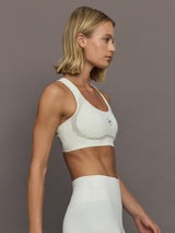 Model wearing a white sports bra with Adidas logo.