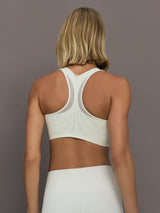 Model wearing a white sports bra with Adidas logo.