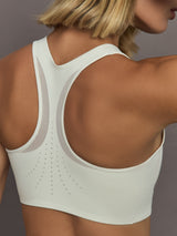 Model wearing a white sports bra with Adidas logo.