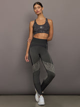 Model wears black/charcoal Adidas sports bra with logo in the center.