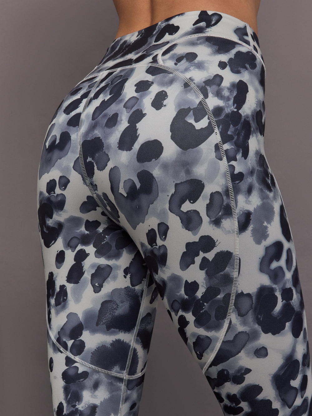 Model is wearing Training Interlock High-Waisted 7/8 Legging in Wonder Alumina/Black, close-up seam and fabric detail.