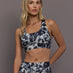 Model is wearing Power Interlock Medium-Support Sports Bra in Wonder Alumina/Black, front chest detail view.