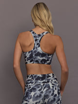 Model is wearing Power Interlock Medium-Support Sports Bra in Wonder Alumina/Black, back racerback view.