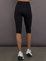 Model is wearing Yoga Interlock High-Waisted Capri Legging in Black, back view.