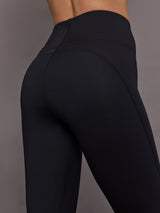 Model is wearing Yoga Interlock High-Waisted Capri Legging in Black, close-up waistband and seam detail.