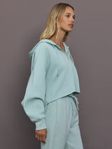 Model is wearing Sportswear Cropped Zip Hoodie in Vapour Green, side view.