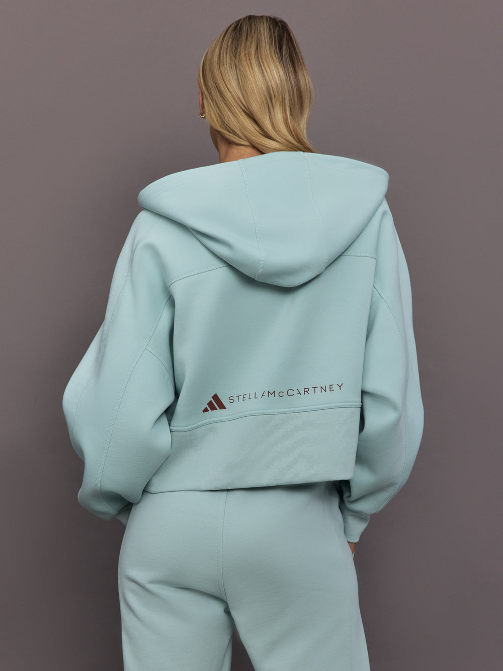Model is wearing Sportswear Cropped Zip Hoodie in Vapour Green, back view.