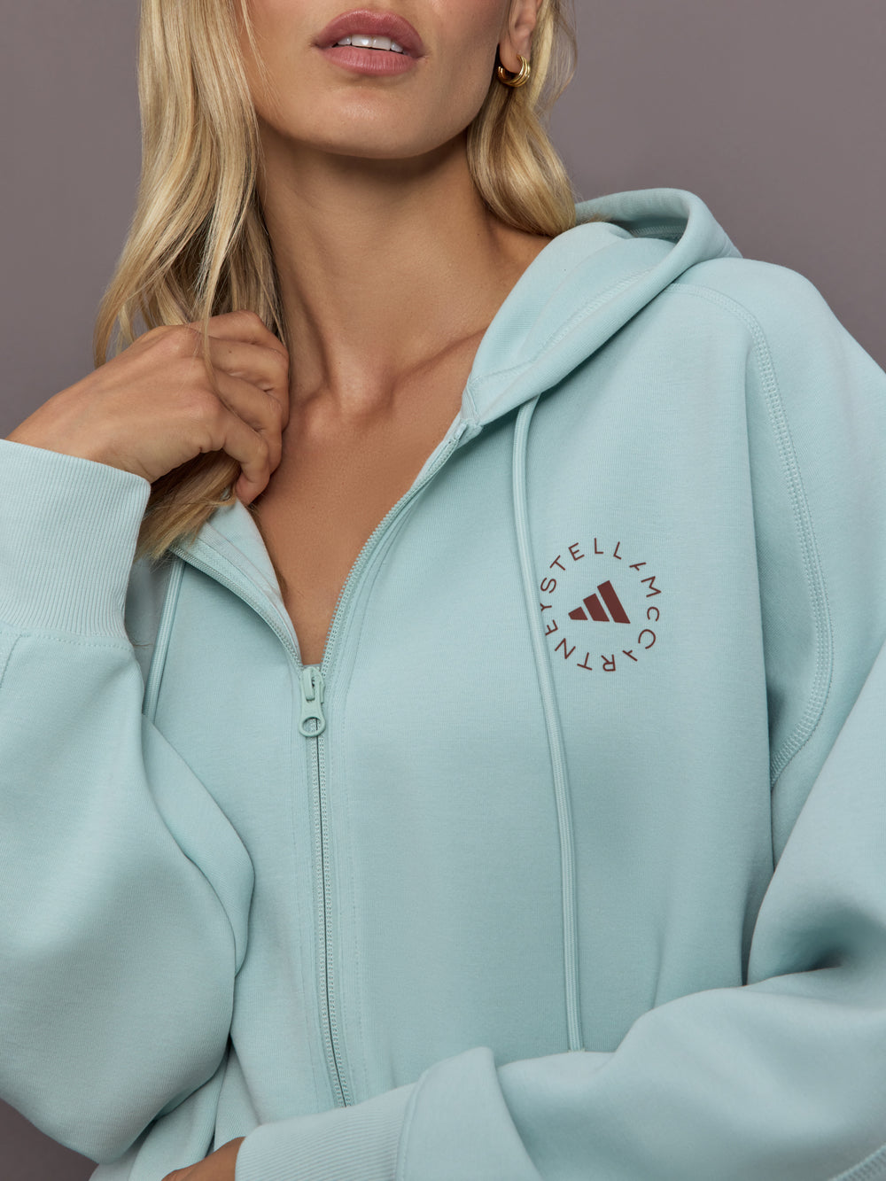 Model is wearing Sportswear Cropped Zip Hoodie in Vapour Green, logo detail close-up.