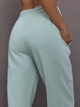 Model is wearing Sportswear Regular Sweatpant in Vapour Green, logo detail close-up.