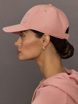 Woman wearing a pink cap and matching hoodie against a gray background