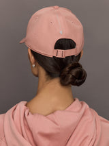 Person wearing a pink cap and matching hoodie against a gray background