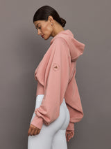 Woman wearing a pink hoodie with a logo on a gray background